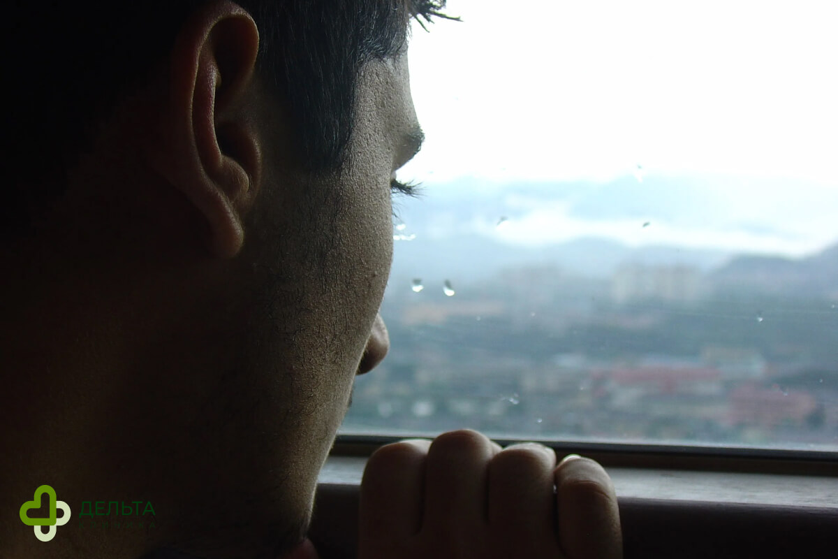 Мужчина смотрит в окно